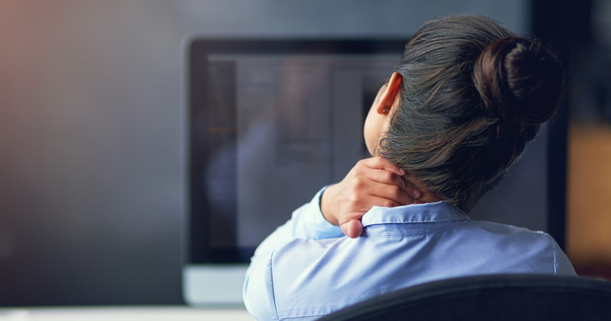 Woman at a computer massaging her neck - office tension.
